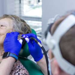 Audiologist performing ear wax removal using microsuction at Malcolm's Pharmacy in Urmston Manchester