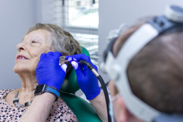 Audiologist performing ear wax removal using microsuction at Malcolm's Pharmacy in Urmston Manchester